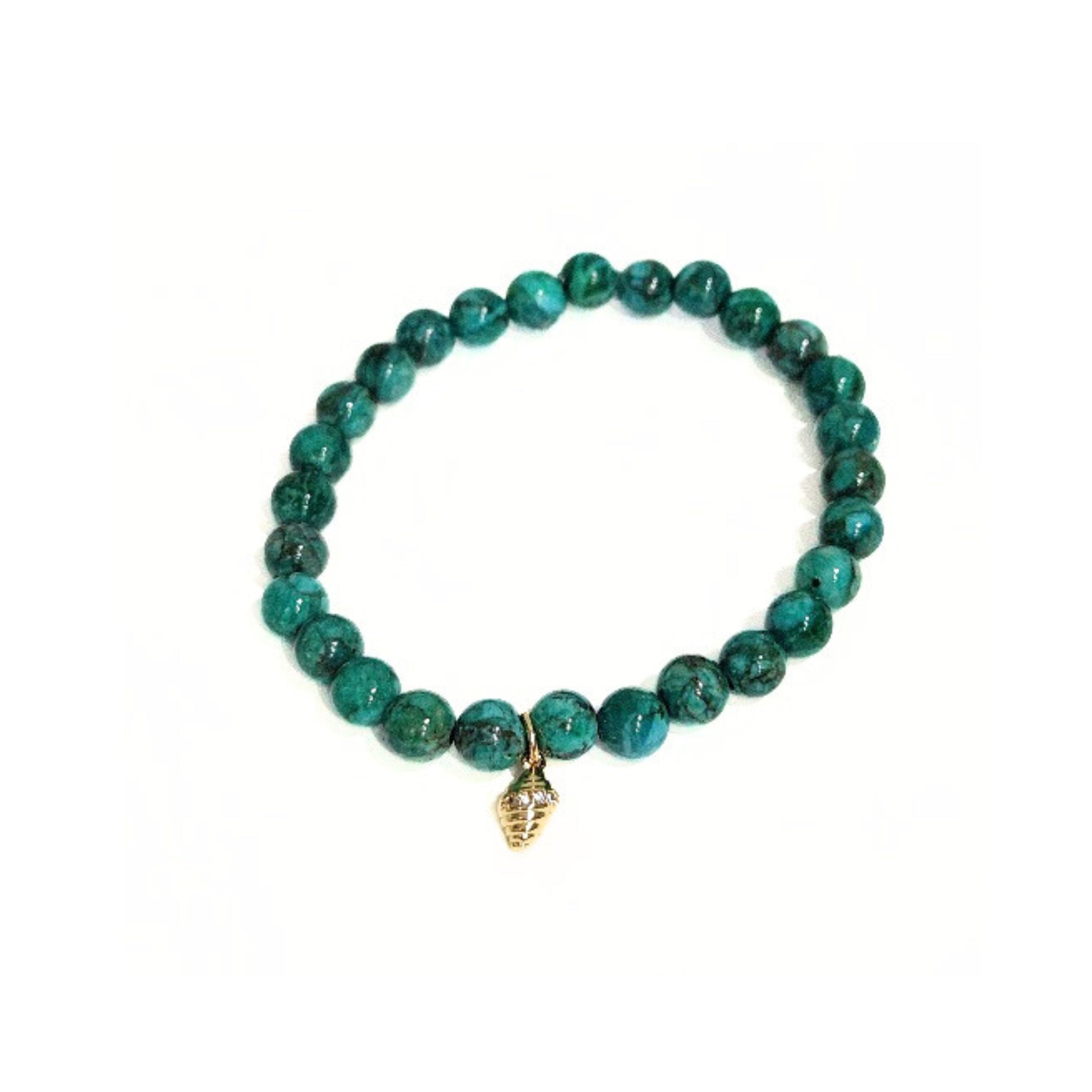 Flat lay view of the Deep Sea African Turquoise stretch bracelet featuring 6mm dark green gemstone beads and gold conch shell charm centered on a crisp white background by Coastline Boutique