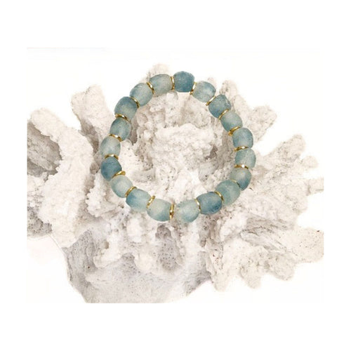 Marine blue recycled glass bracelet with gold accents draped over a white coastal reef decor piece on a clean white background