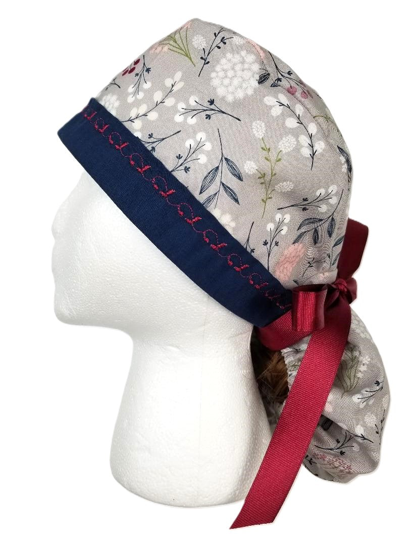 Slate gray and white floral surgical cap with olive greenery and a navy blue headband featuring signature cranberry designer stitching by Coastline Boutique