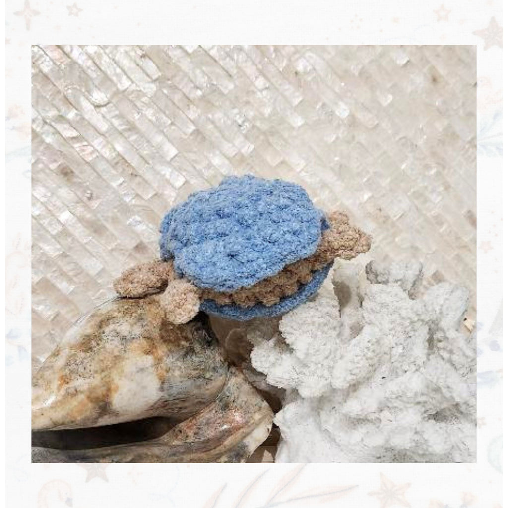 A Unique back-angle of Crabulous scuttling along, showcasing the vibrant blue sun hat and the sandy-colored crochet legs in motion by Coastline Boutique