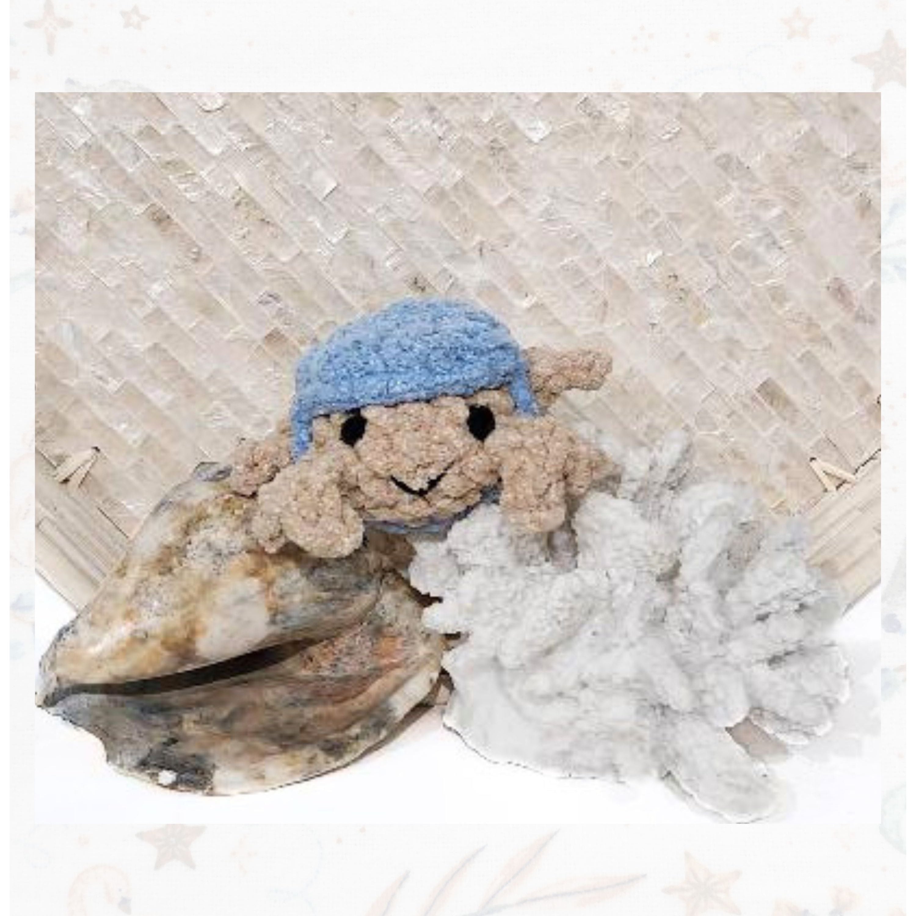 Front view of a handmade amigurumi crab with sandy-colored yarn, a bright blue corcheted hat, and a friendly face