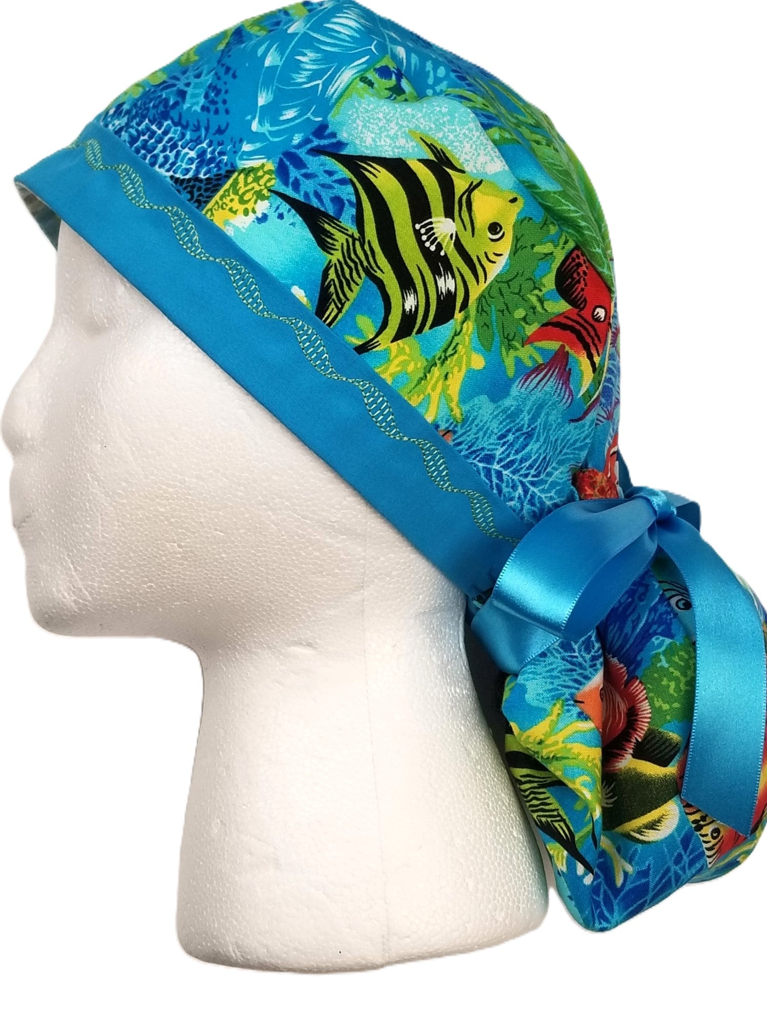 Vibrant tropical fish surgical cap featuring vivid yellow, red, orange fish with black accents and a designer-stitched headband by Coastline Boutique