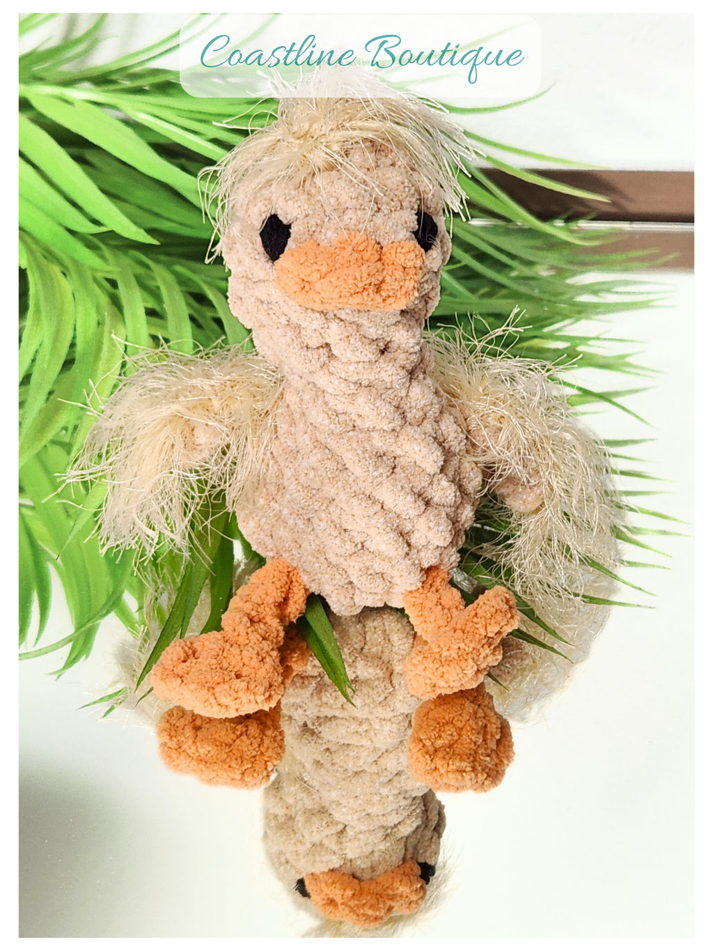 Front facing portrait of Nugget the Gosling sitting on a mirror showcasing the reflected handmade crochet details of the chin and underside
