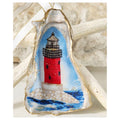 Handcrafted gilded oyster shell ornament featuring a classic red lighthouse on a nautical blue background, finished with an elegant white ribbon and hand-painted gold leaf trim.