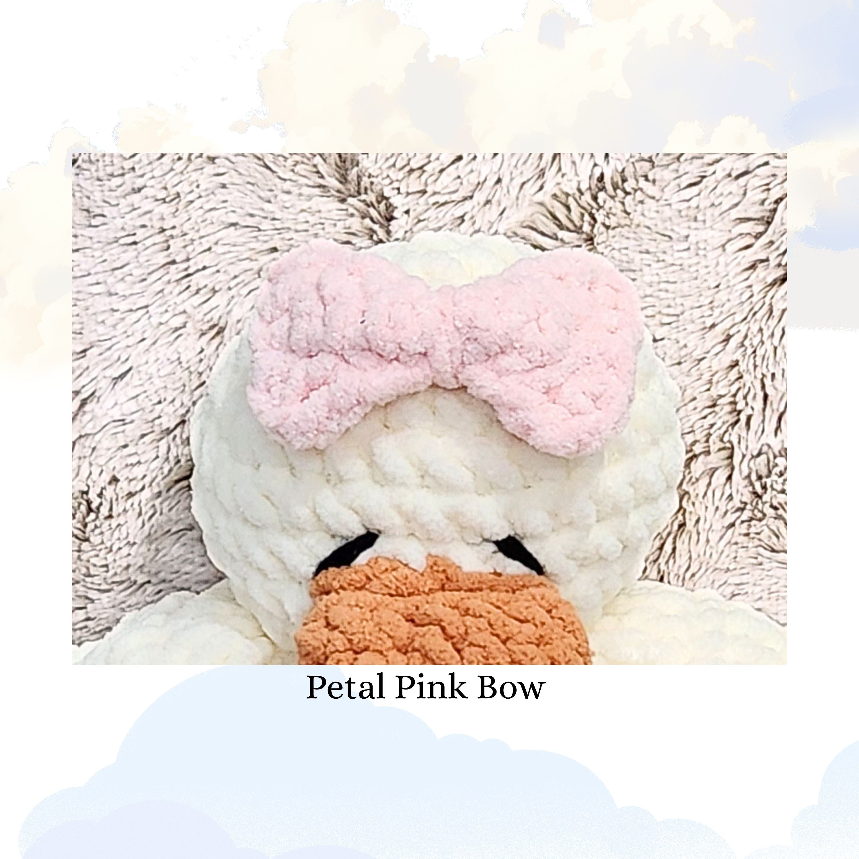 Close up detail of a handmade petal pink yarn bow on a vanilla cream duck snuggler, showcasing the delicate pink color and intricate crochet texture