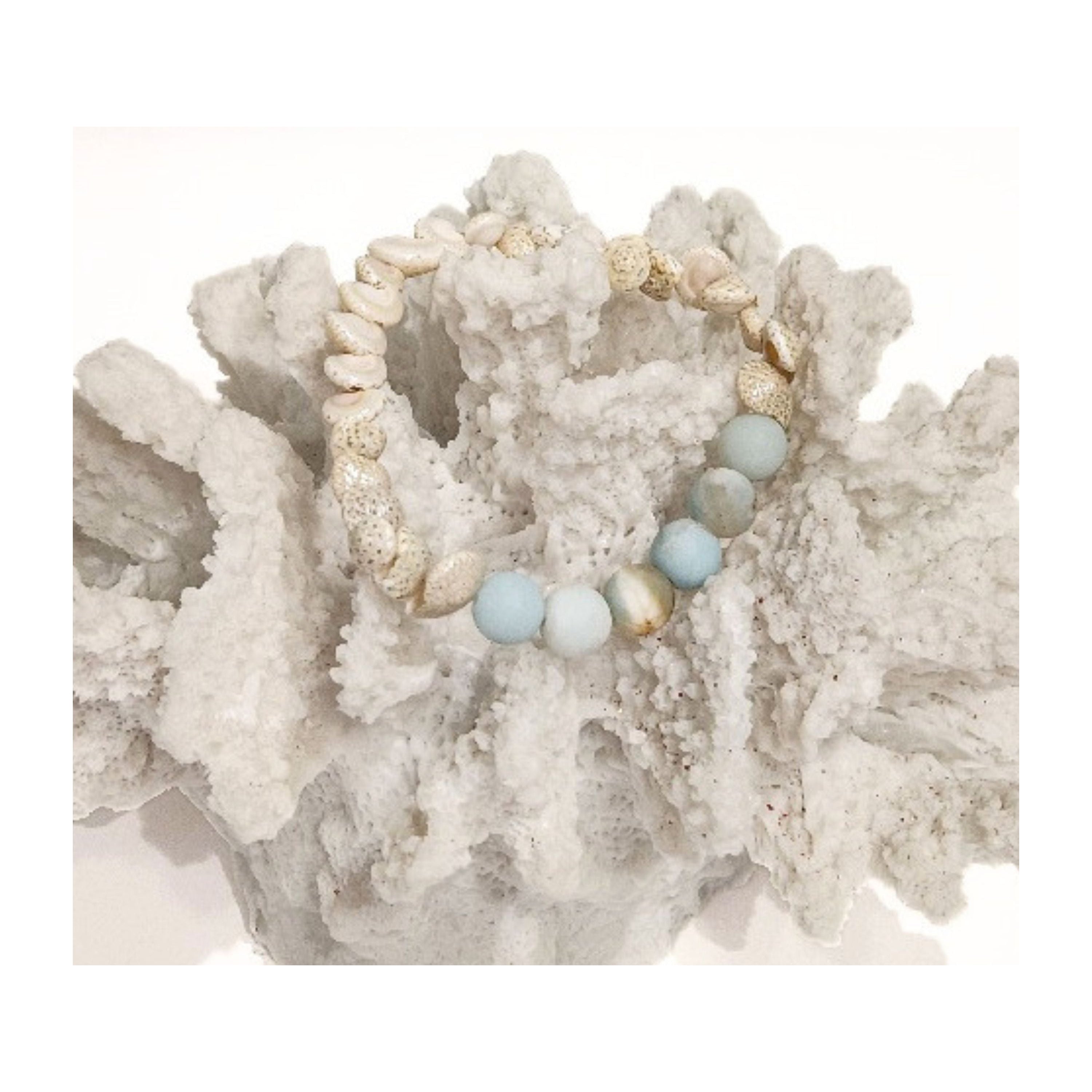 Close up of the Sands of Serenity shell bracelet resting on white reef coral, highlighting the natural textures by Coastline Boutique