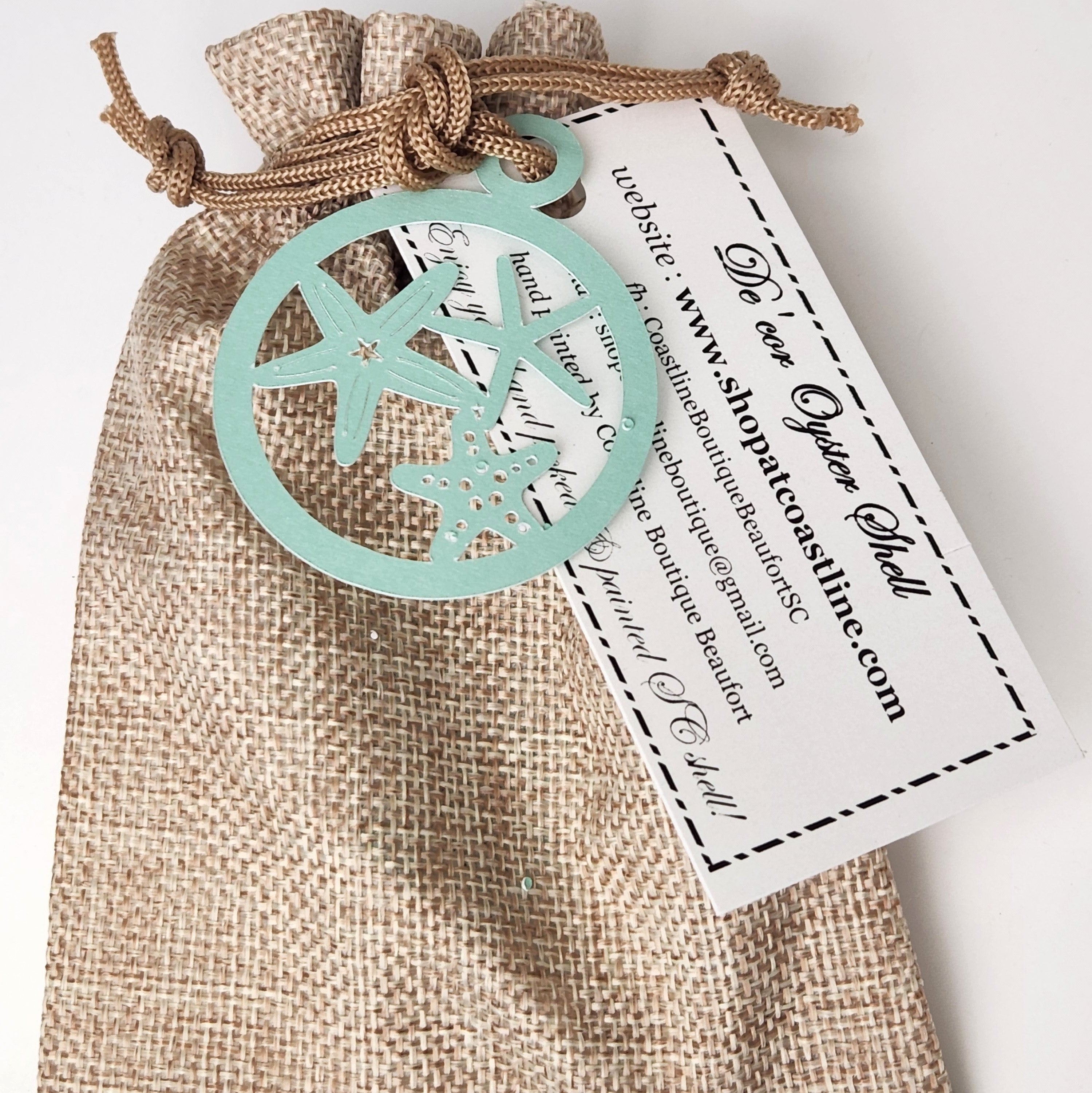 Burlap gift pouch with a drawstring closure, featuring a sea-green starfish paper tag that reads Decor Oyster Shell tied to the front.
