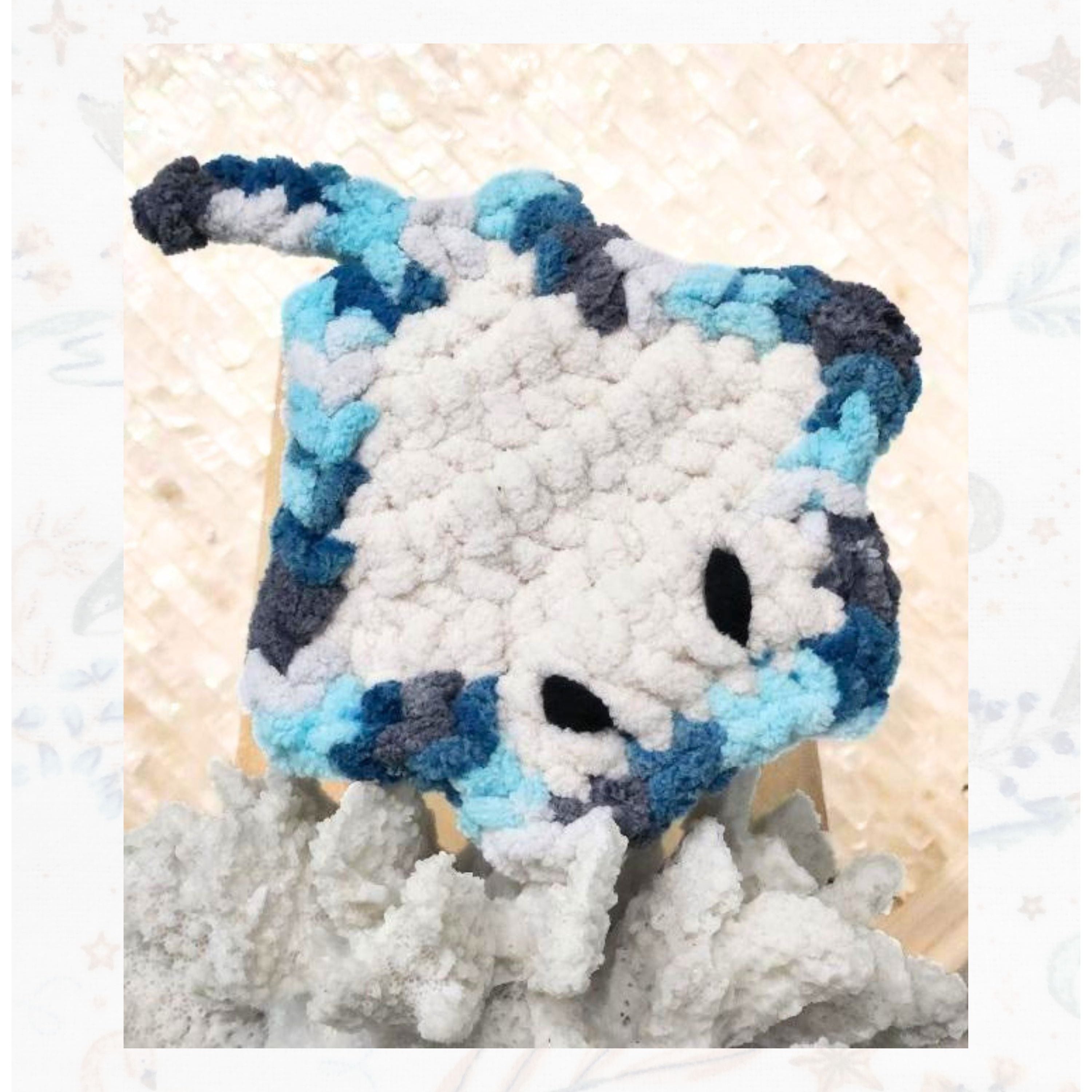 A baby crochet stingray named Sol from the Brejoy Collection, pictured in a playful nose-down pose on a white reef, handcrafted by Coastline Boutique.
