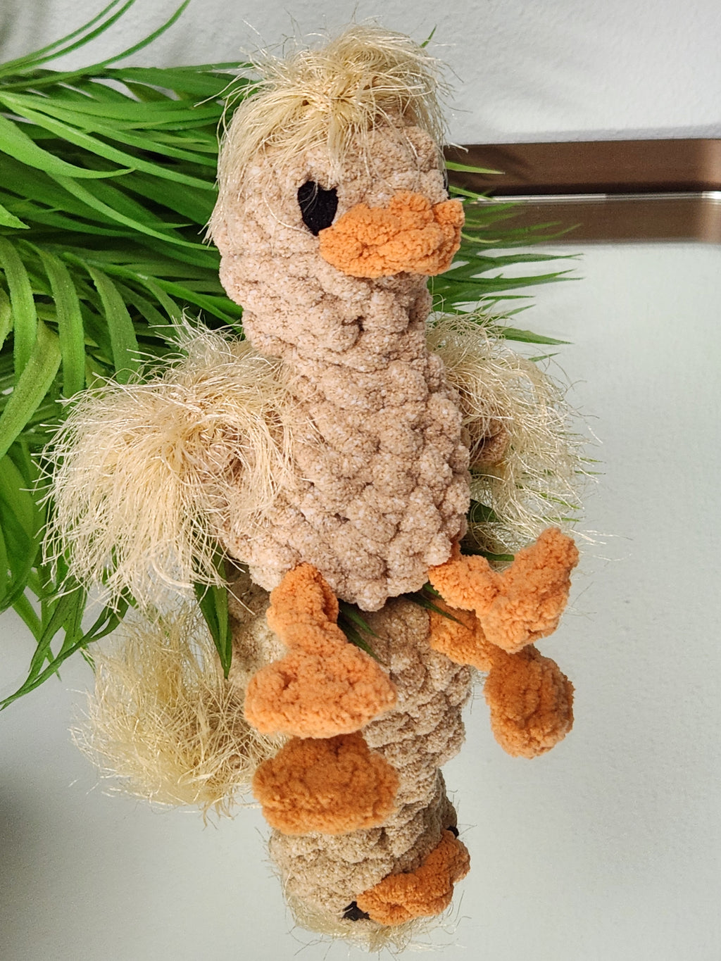 A three quarter view of Nugget the Gosling on a mirror showcasing reflected details of the chin bottom of the feet and textured wing stitching