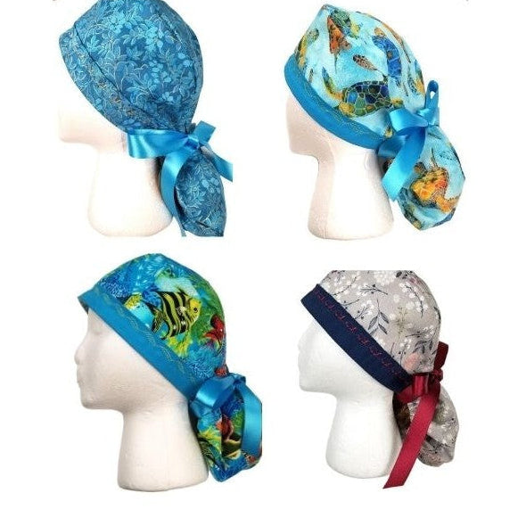 Collection of Coastal Artisan surgical ponytail caps featuring sea turtles, fish, turquoise gilded accents and winterberry patterns by Coastline Boutique