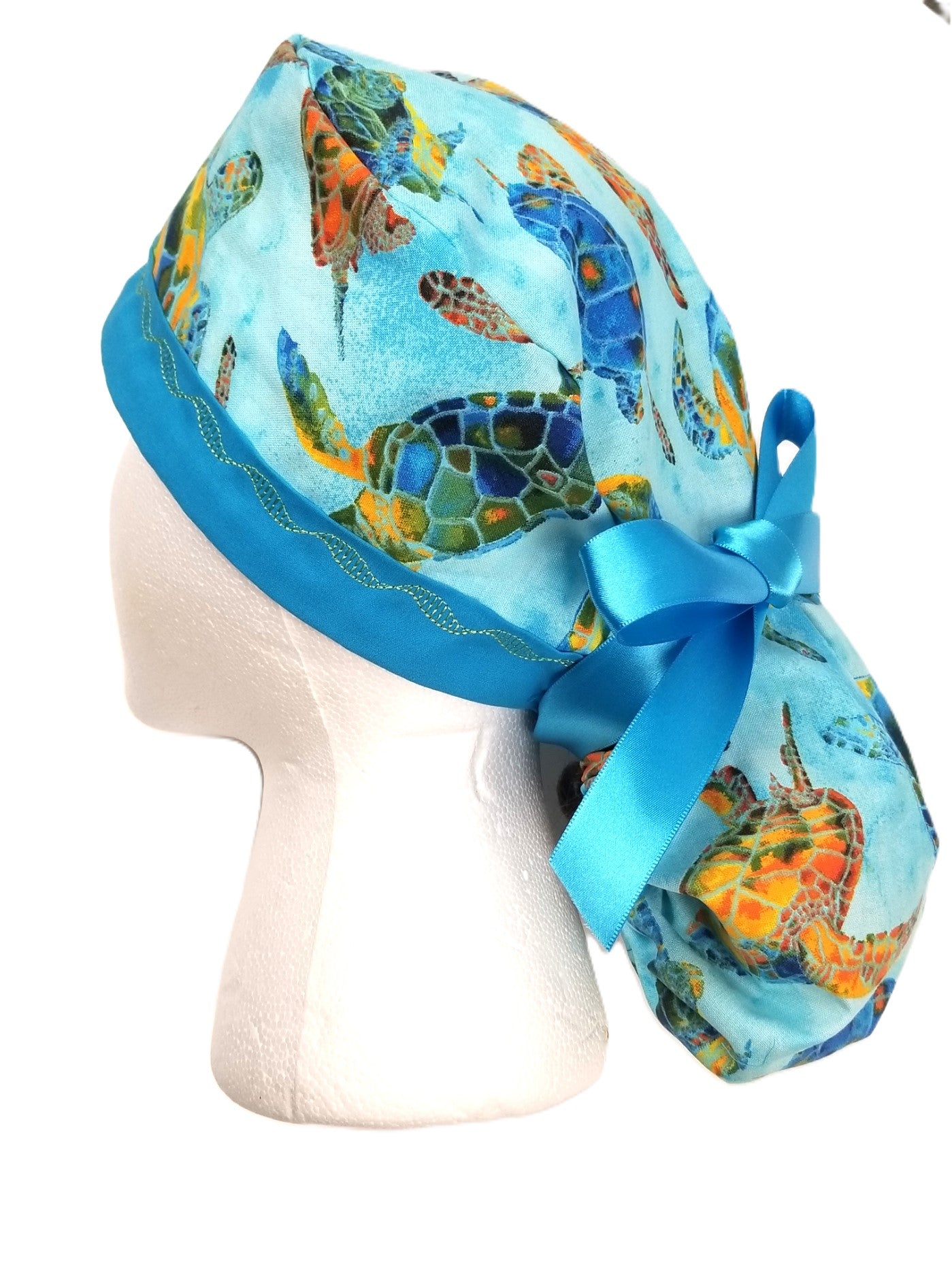 Coastal sea turtle print ponytail surgical cap in a tranquil blue, orange, yellow and green palette with a coordinating designer-stitched headband by Coastline Boutique